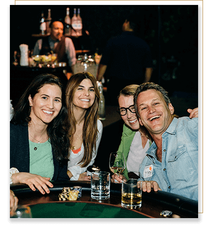 Image of four people laughing and smiling together at a poker table.