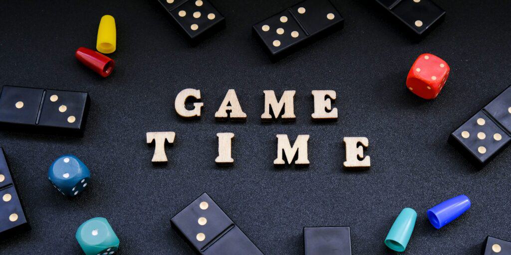 A tile sign saying Game Time surrounded by dominos, dice, and game pieces. 