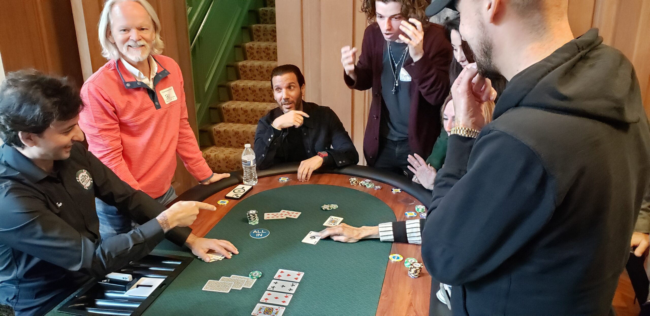 three people watchign a poker hand playing out with shocked looks on their faces