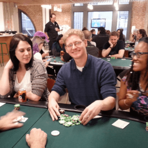 three happy employees playing poker at work during a team building event
