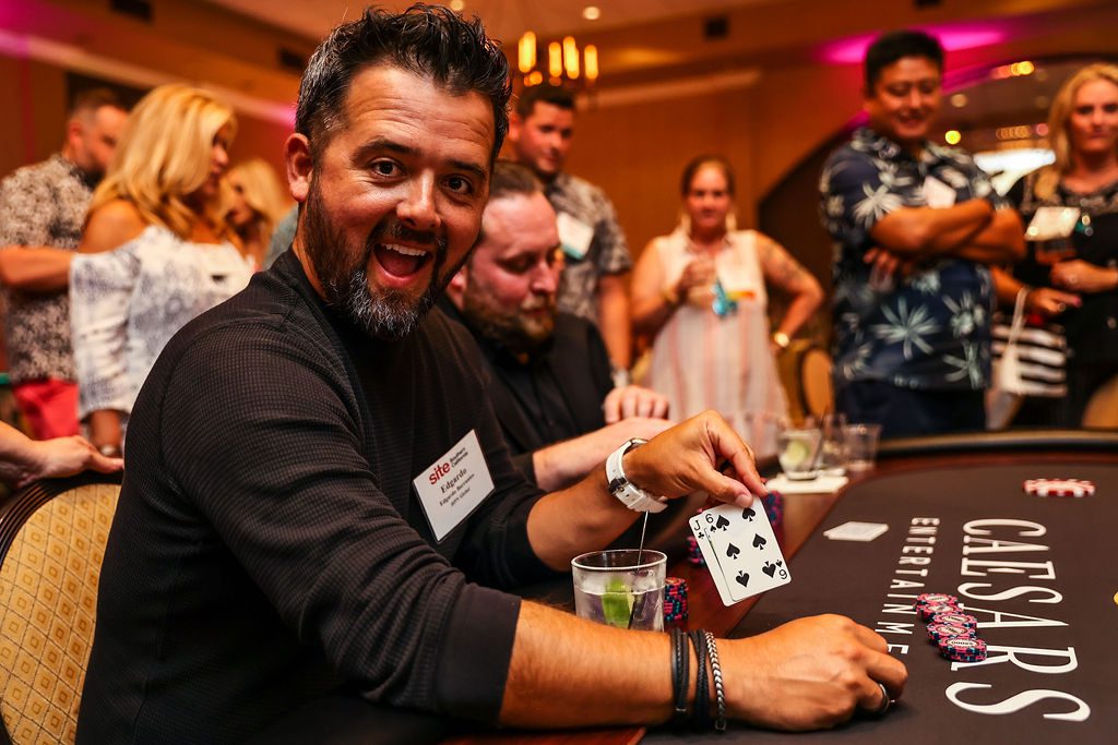 a man in a black shirt is playing poker and showing his cards to the camera