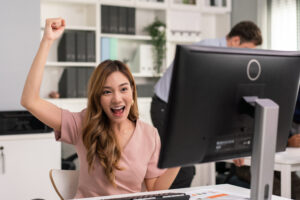 Woman in the office celebrates playing poker. One of the best virtual team building activities.