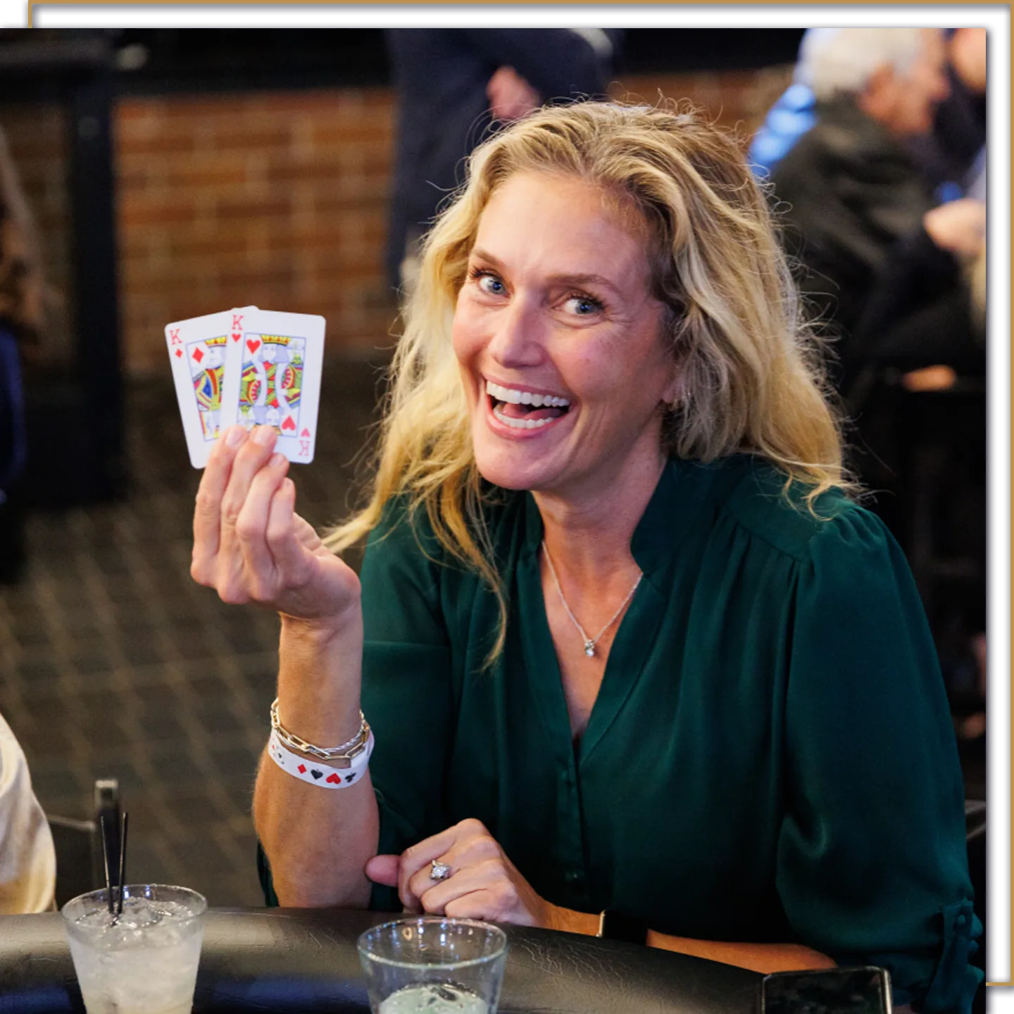 A woman in a green shirt holds up pocket kings at a team building poker tournament